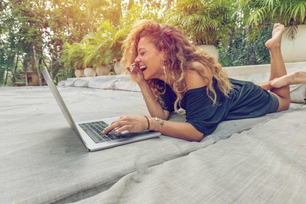 woman laughing while working on her laptop